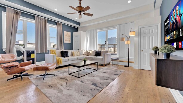 A spacious living room with a sofa, coffee table, and a TV mounted on the wall. - Charming 2BD by Independence Hall | Sleeps 6 (Philadelphia)