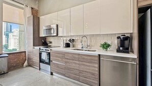 A modern kitchen with white cabinets, stainless steel appliances, and a view of the city.