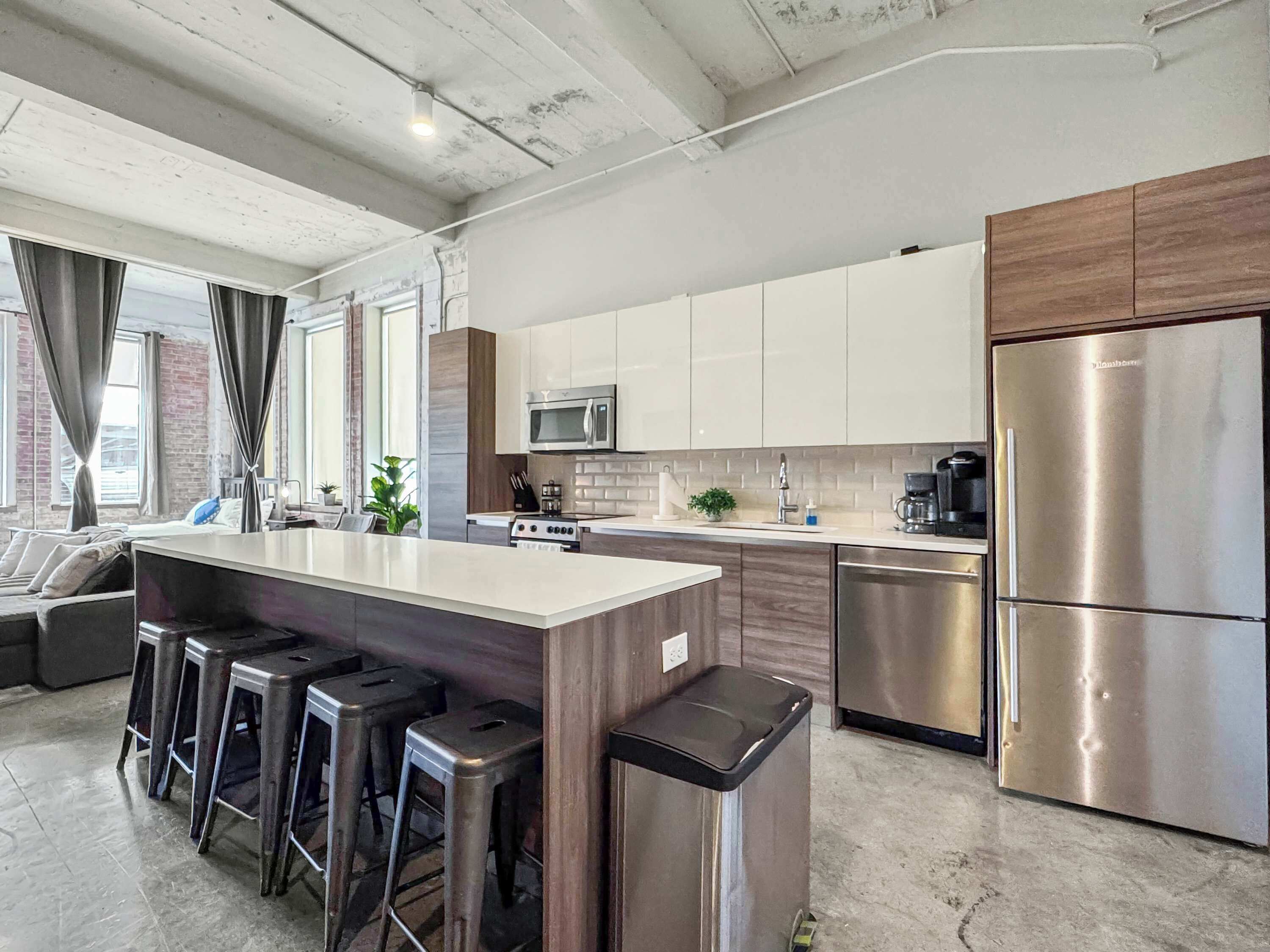 Een moderne keuken met een centraal eiland, roestvrijstalen apparatuur en barkrukken.