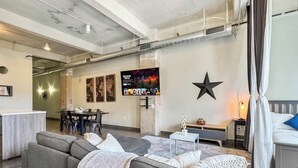 Un salon moderne avec un canapé d’angle, un téléviseur à écran plat fixé au mur et une décoration en forme d’étoile.