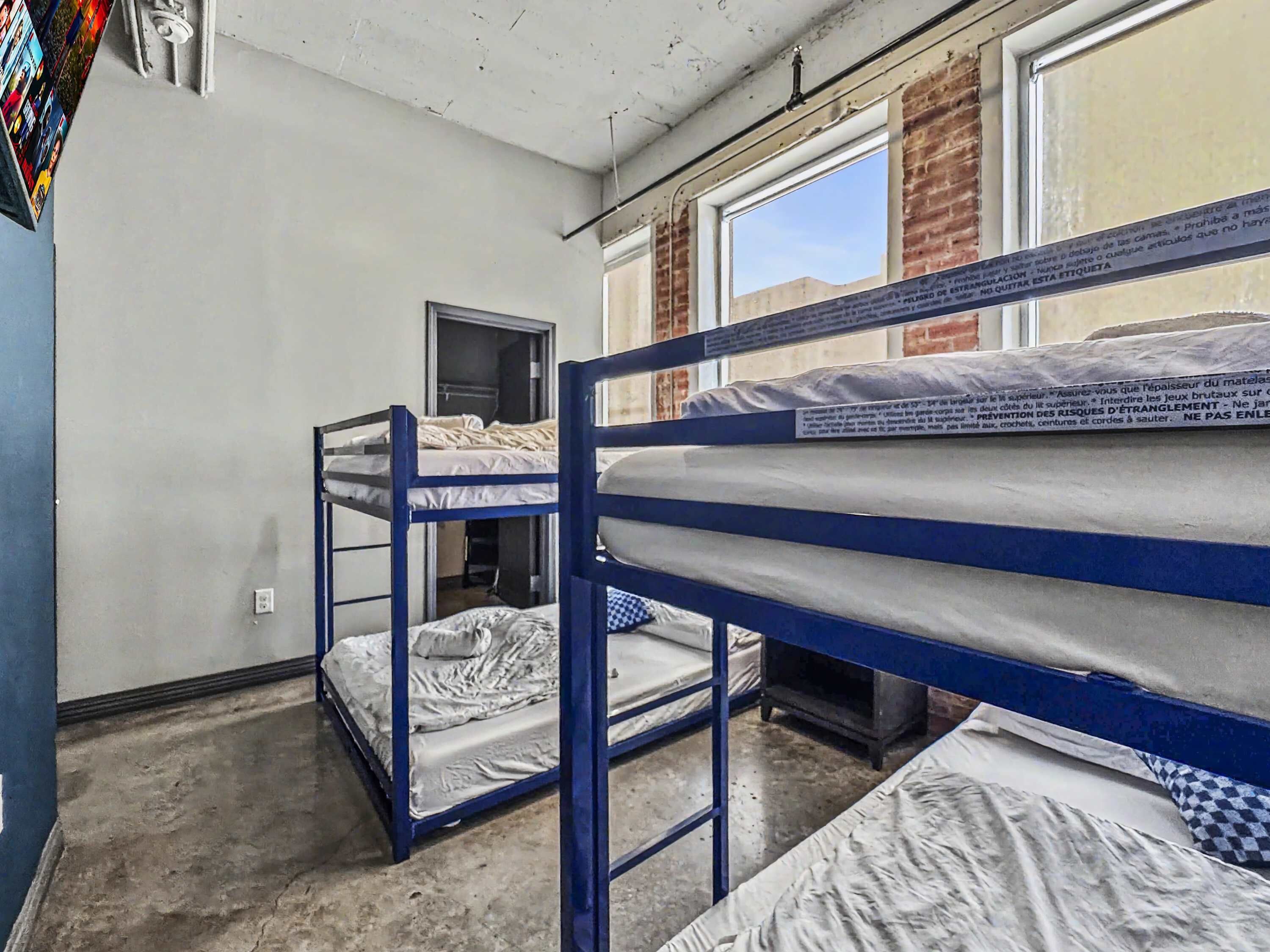 A dormitory room with bunk beds, a window, and a door.