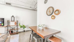 Un coin repas avec une table en bois, des tabourets en métal, une plante et des assiettes décoratives accrochées au mur.