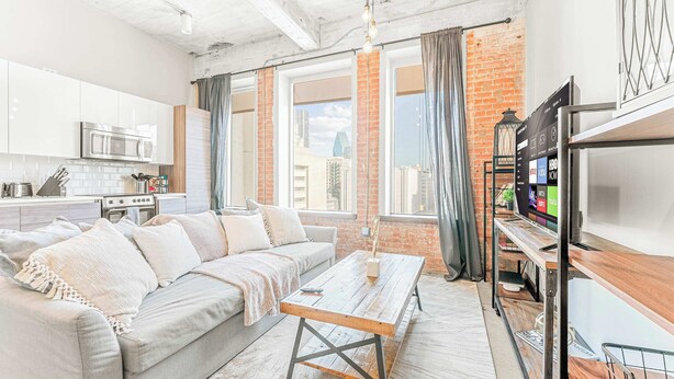 Un salon moderne avec un canapé, une table basse et un téléviseur posé sur un meuble.