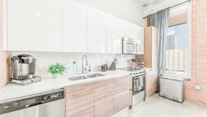 Une cuisine moderne avec des meubles blancs, une machine à café, un four à micro-ondes et un lave-vaisselle.