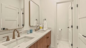 Een moderne badkamer met twee wastafels, een grote spiegel en houten kastjes.