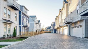 A residential street with townhouses, paved sidewalks, and a wooden fence.