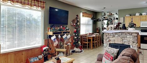 A cozy living room with a fireplace, a dining area, and a kitchen.