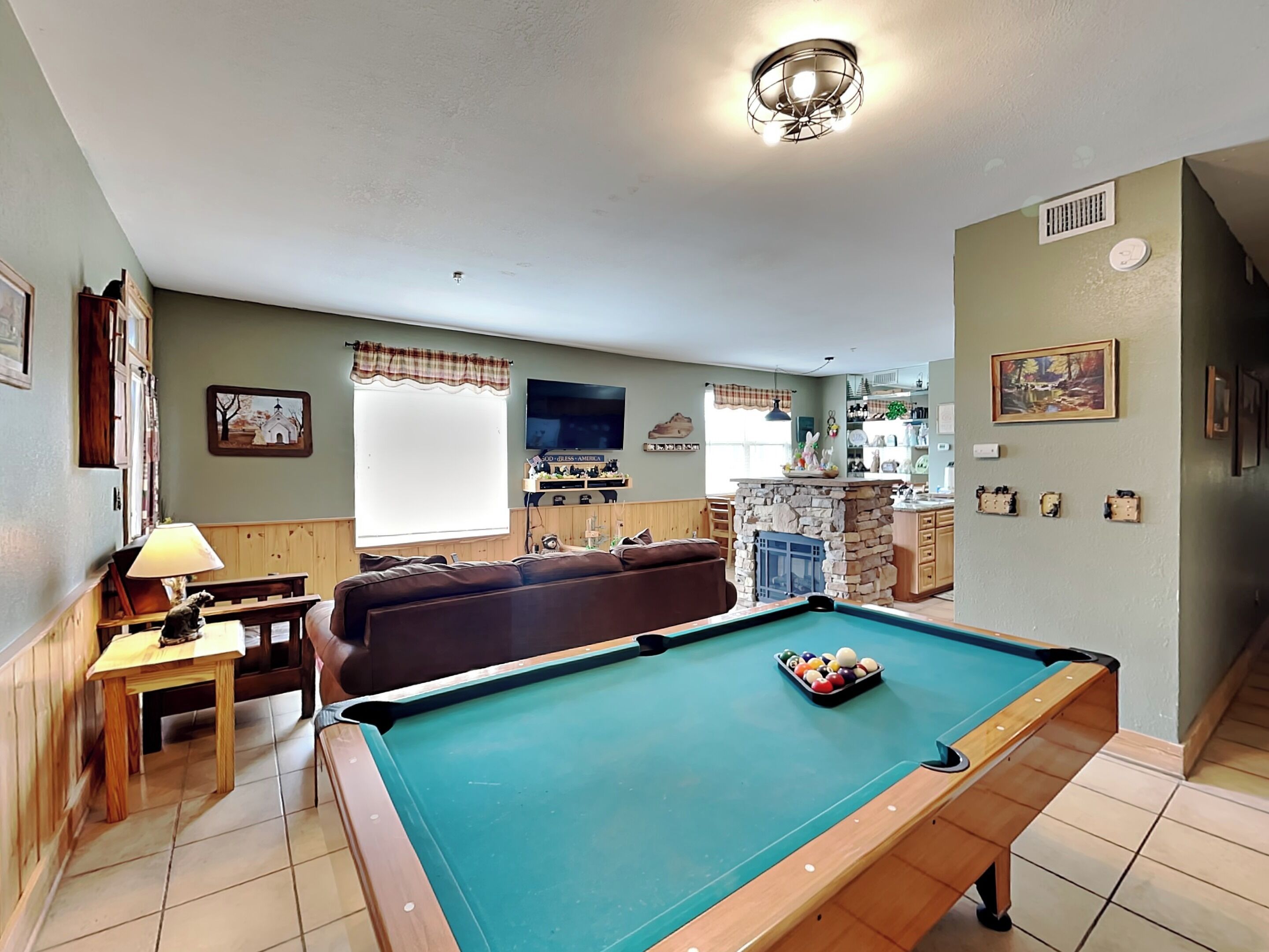A cozy living room with a pool table, a sofa, and a fireplace.