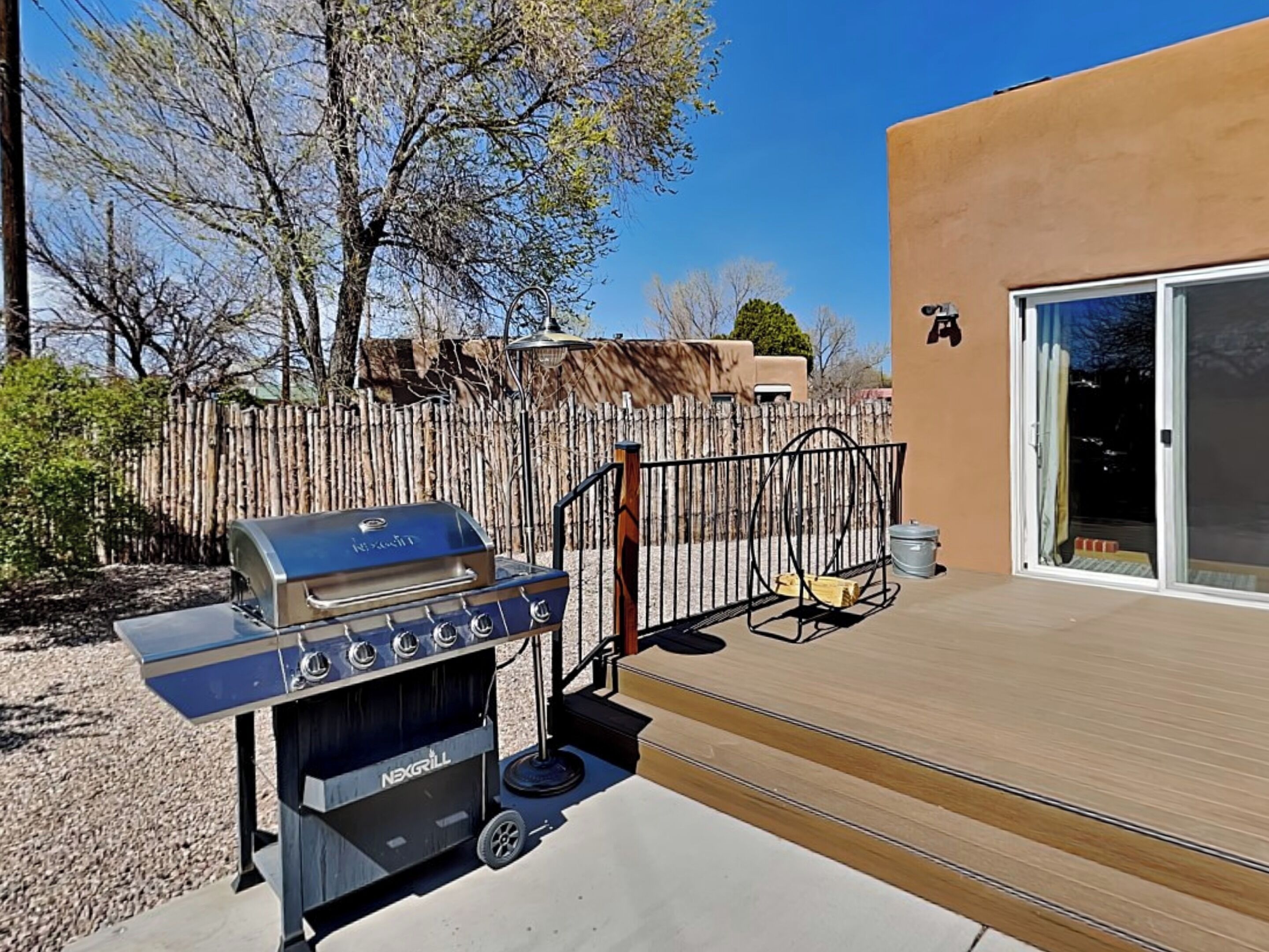 A barbecue grill and a trash can on a wooden deck.