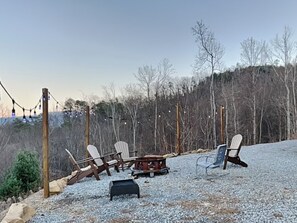 A gravel outdoor seating area with Adirondack chairs, a fire pit, and string lights. - 5 Solas Lodge by Jackson Mountain Rentals (Sevierville)