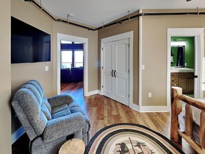 A living room with a gray sofa, a flat-screen TV, and a wooden floor. - 5 Solas Lodge by Jackson Mountain Rentals (Sevierville)