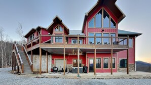 Un grand immeuble à étages, doté d’une façade rouge imposante, de nombreux balcons et d’un espace extérieur couvert aménagé avec des sièges.