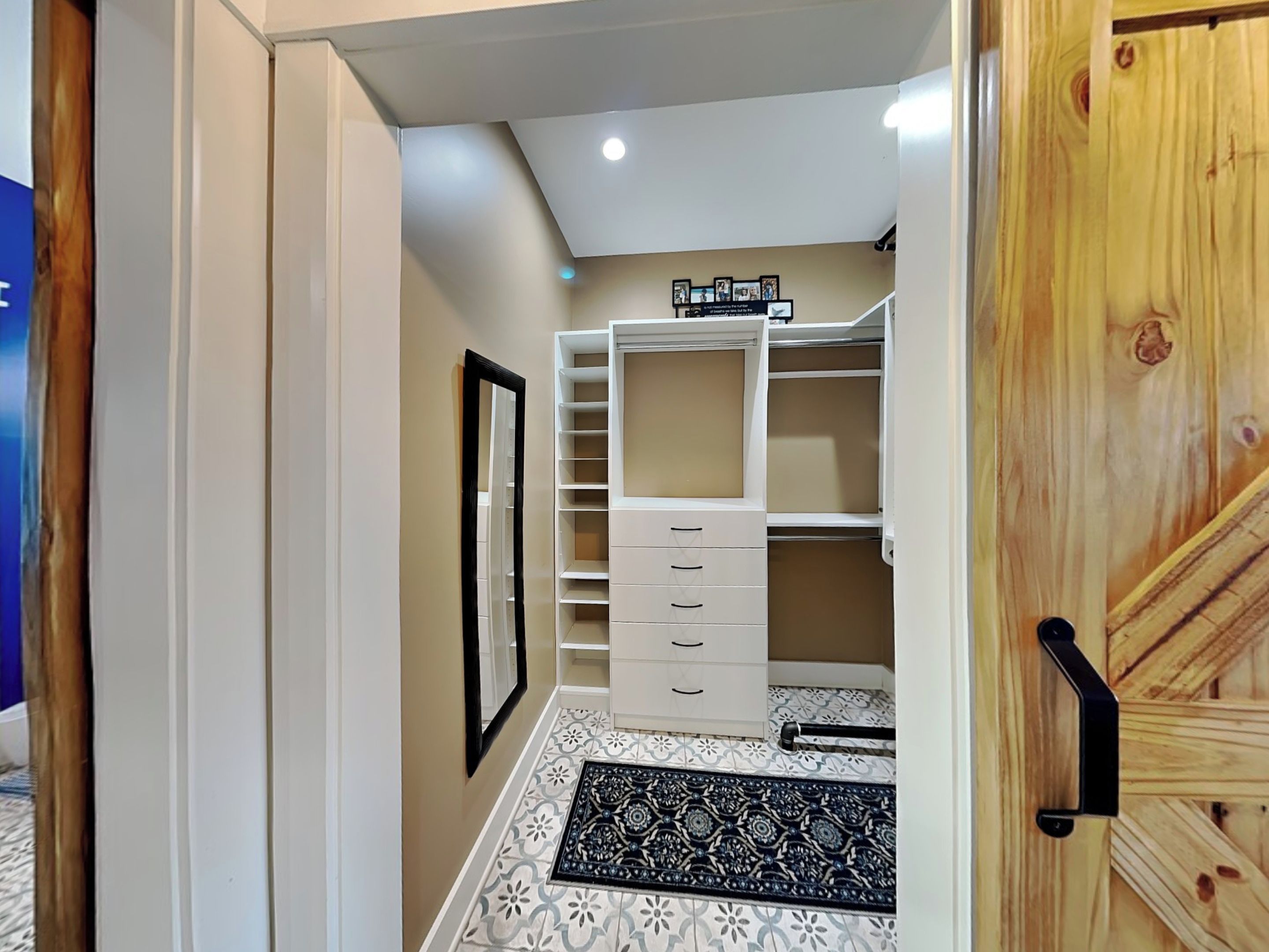 A walk-in closet with open shelving, drawers, and a mirrored closet door.