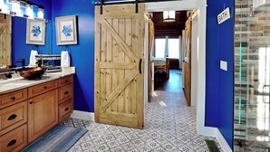 Une salle de bain avec un mur bleu, une porte en bois, un lavabo avec un receveur et une pancarte indiquant « SALLE DE BAIN ».