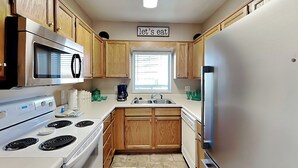 Una cocina con armarios de madera, un refrigerador de acero inoxidable, un microondas, una estufa y un lavaplatos.