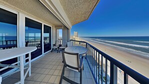 A balcony with a view of the beach and ocean.