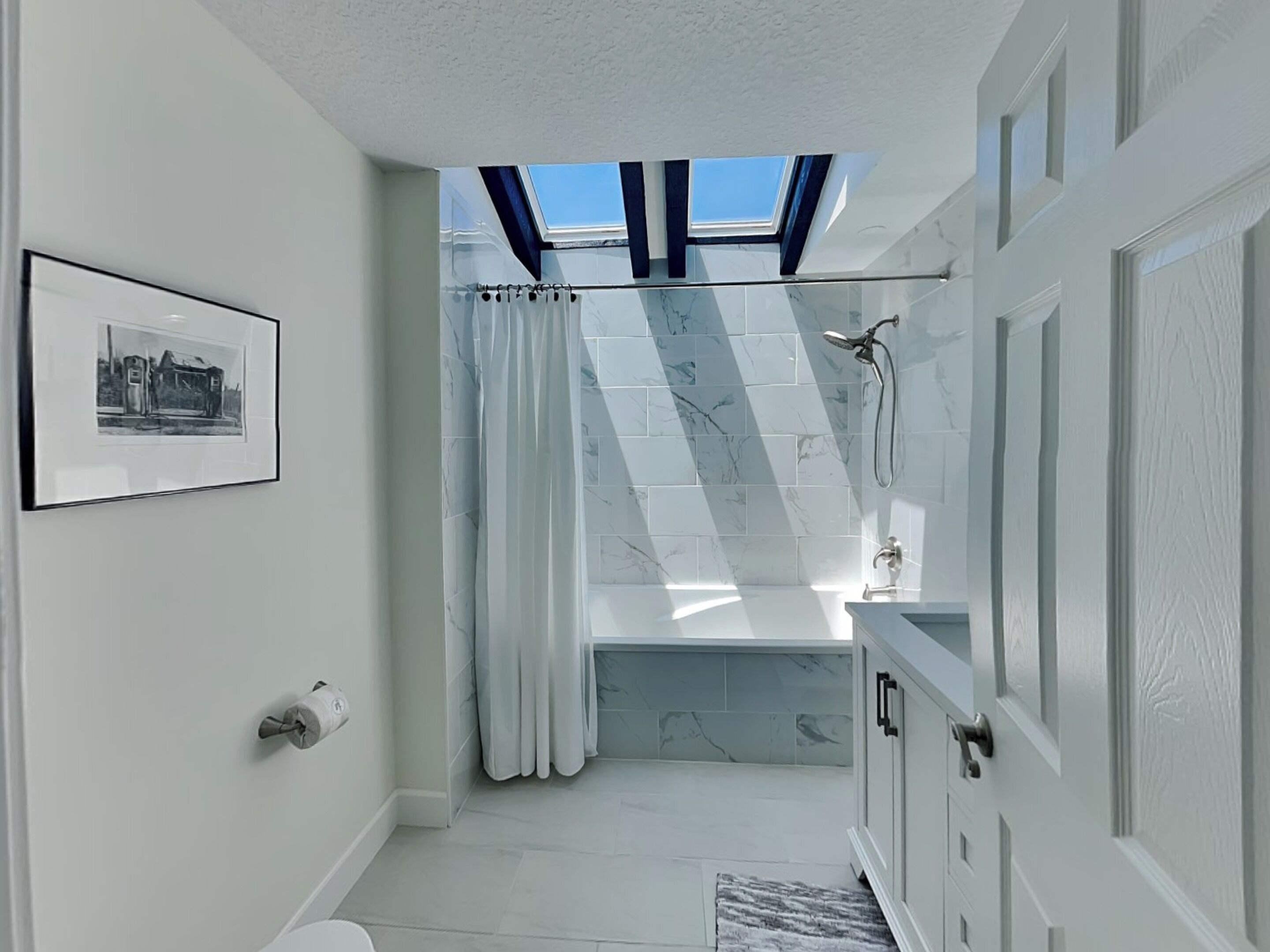 A modern bathroom with a skylight, a bathtub, and a shower.