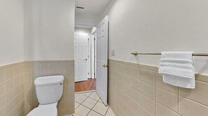 A bathroom with a toilet, a towel rack, and a door leading to another room.