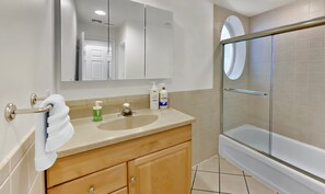 Un baño con lavamanos, espejo y cabina de ducha con mampara de vidrio.