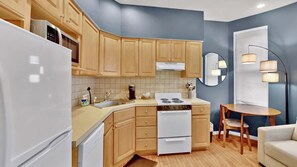 Una cocina con armarios de madera, una estufa blanca y un comedor con mesa y sillas.