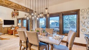 A dining area with a large table, chairs, and a view of the outdoors. - Winterhaven Estate by Avantstay Sleeps 19 Guests Mountain Compound w/ Views, Firepit, Hot Tub (Winter Park)