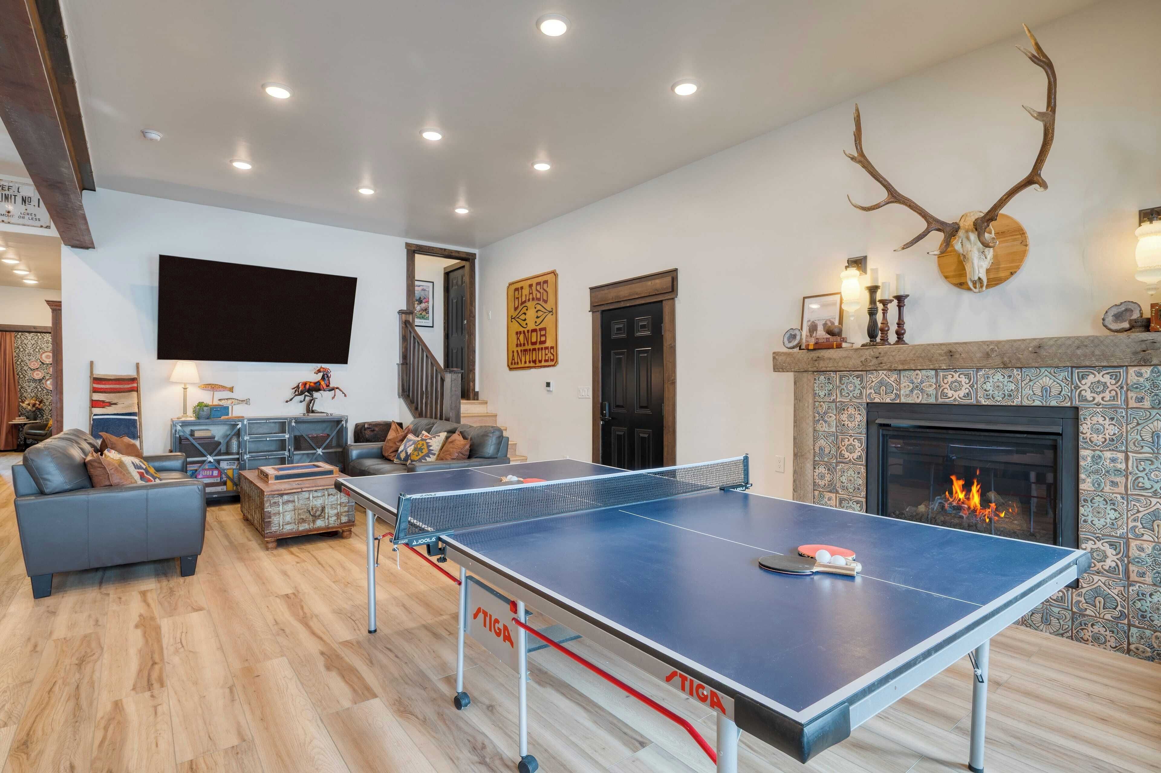 Una sala de estar con mesa de ping pong, chimenea y cráneo de ciervo montado.