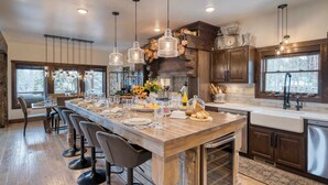 A spacious kitchen with a long island, pendant lighting, and a view of the outdoors.