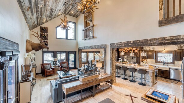 A spacious living area with a high ceiling, rustic decor, and a large dining area with bar stools.