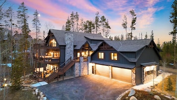 A multi-story log cabin with a stone facade, a second-story balcony, and a garage.
