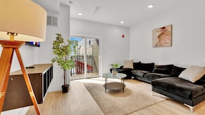A modern living room with a sofa, a coffee table, a lamp, and a potted plant.