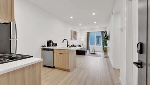 A modern kitchen with a dishwasher, stove, and a small dining area with a table and chairs.