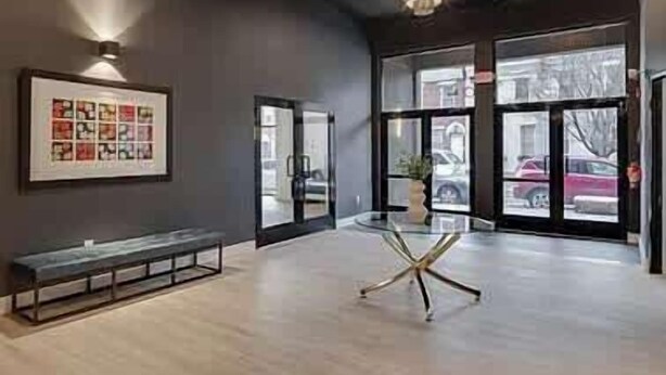 A modern interior with a bench, a glass table, and a chandelier.