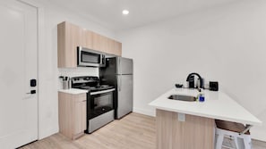 Una cocina moderna con microondas, estufa, refrigerador y pileta.