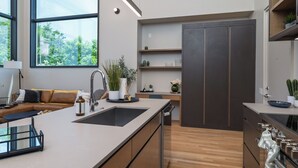A modern kitchen with a large island, built-in appliances, and a view of greenery outside. - Cultural District Loft, Rooftop Terrace + Games (Fort Worth)