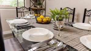 A dining table set with white plates, silverware, and glasses, accompanied by a basket of lemons and a potted plant. - Canyon Lake Retreat by The Key Rentals (Canyon Lake)