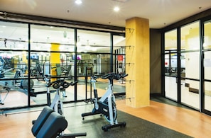 Ett gym med träningsutrustning, stora fönster och en träkolonn.