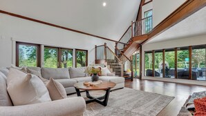 Ein geräumiges Wohnzimmer mit einem großen Sofa, einem Couchtisch und einer Treppe, die in ein Obergeschoss führt.