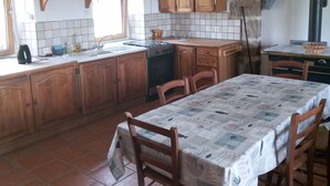 A kitchen with wooden cabinets, a tiled backsplash, a stove, and a dining table with chairs.