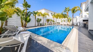 Une piscine avec des chaises longues et des palmiers.