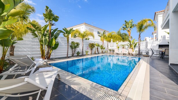 Una piscina con sillas de descanso y palmeras.