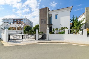 A modern residential building with a white facade, a wooden slatted section, and a gated entrance. - Blue Pelagos Villa in Protaras (Paralimni)