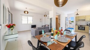 Ein modernes Wohnzimmer mit Essbereich, einer Küche und Blick auf das Meer.