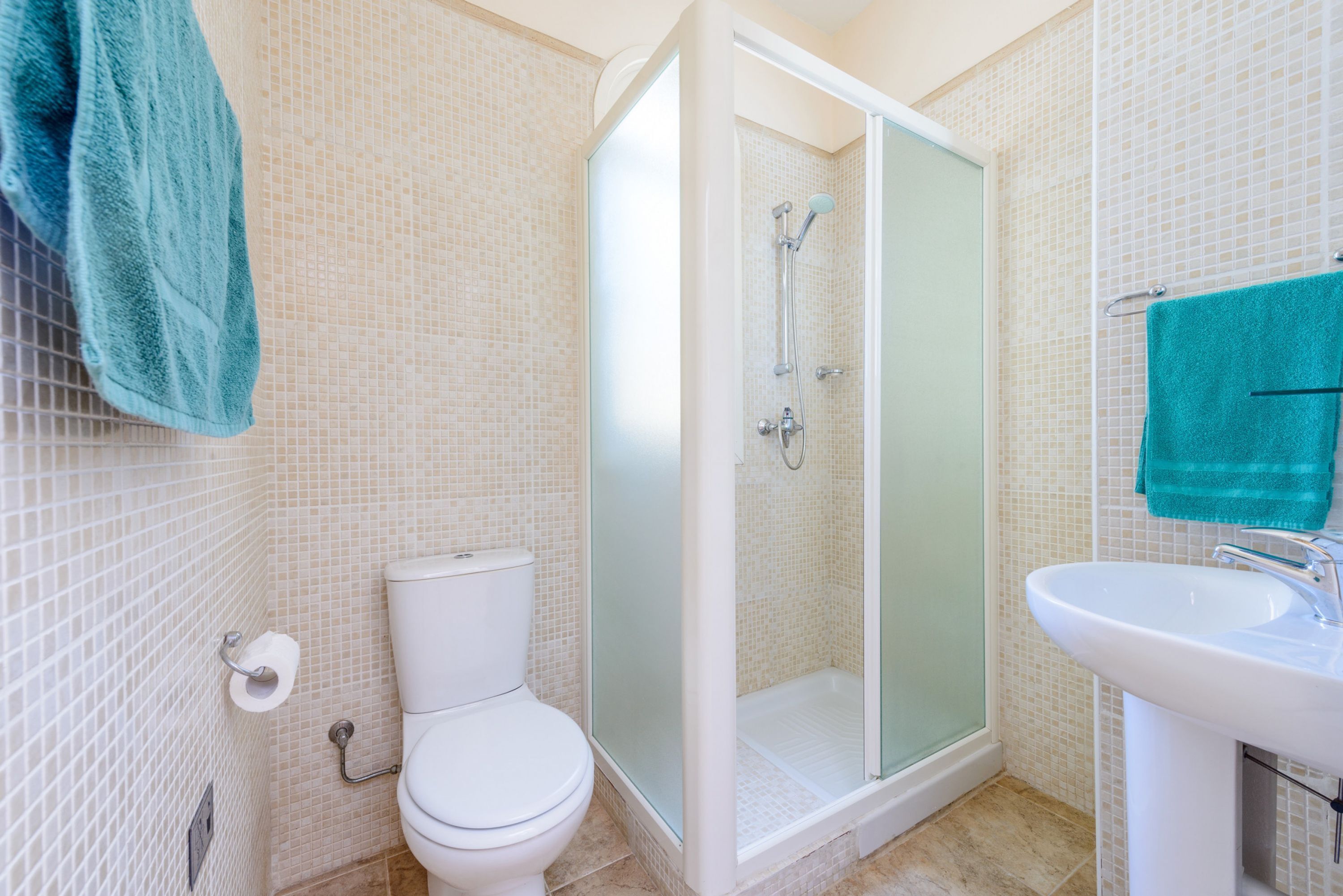 Et badeværelse med toilet, et glasvægshus og en vask.