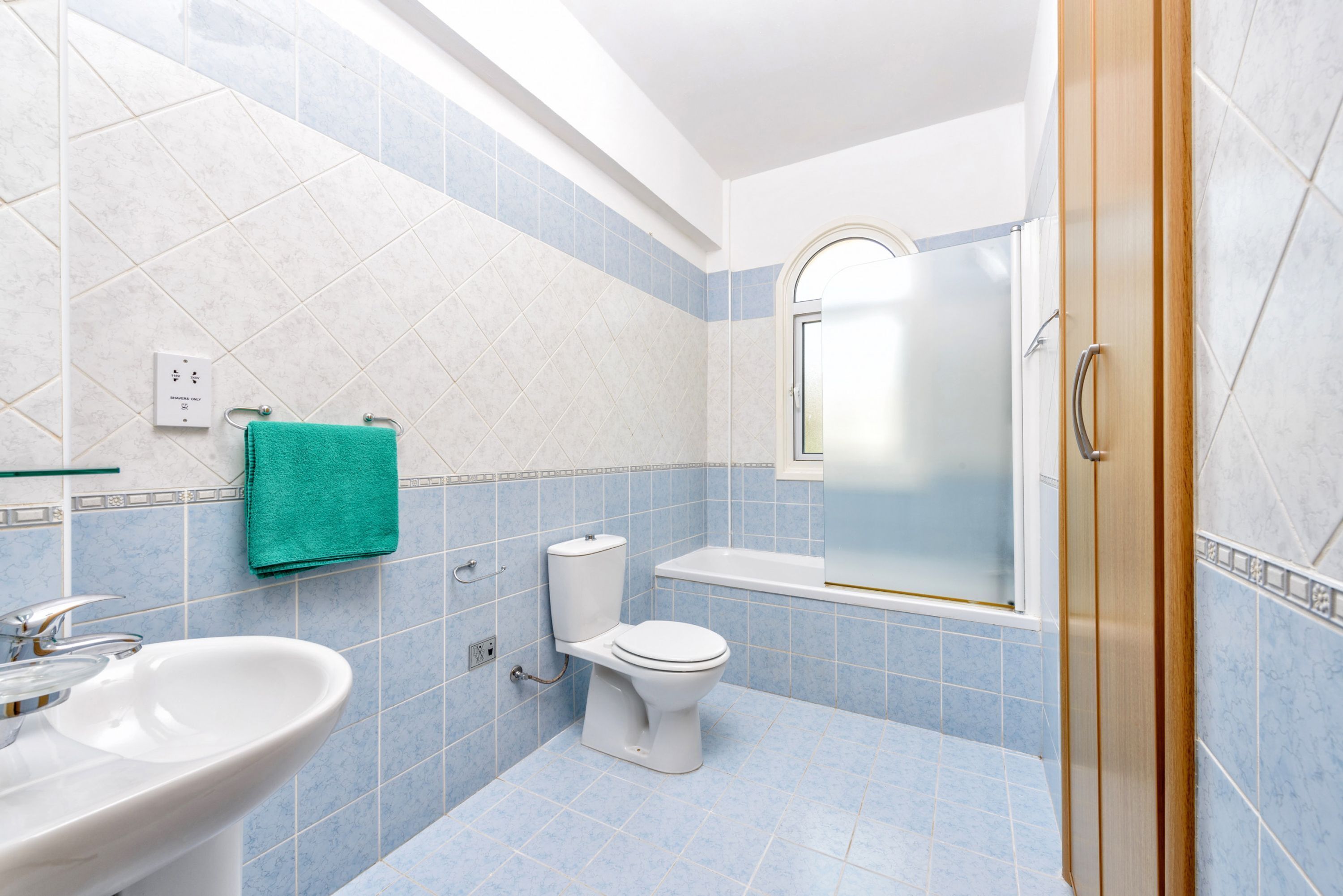 Et badeværelse med vask, toilet og brusebad.