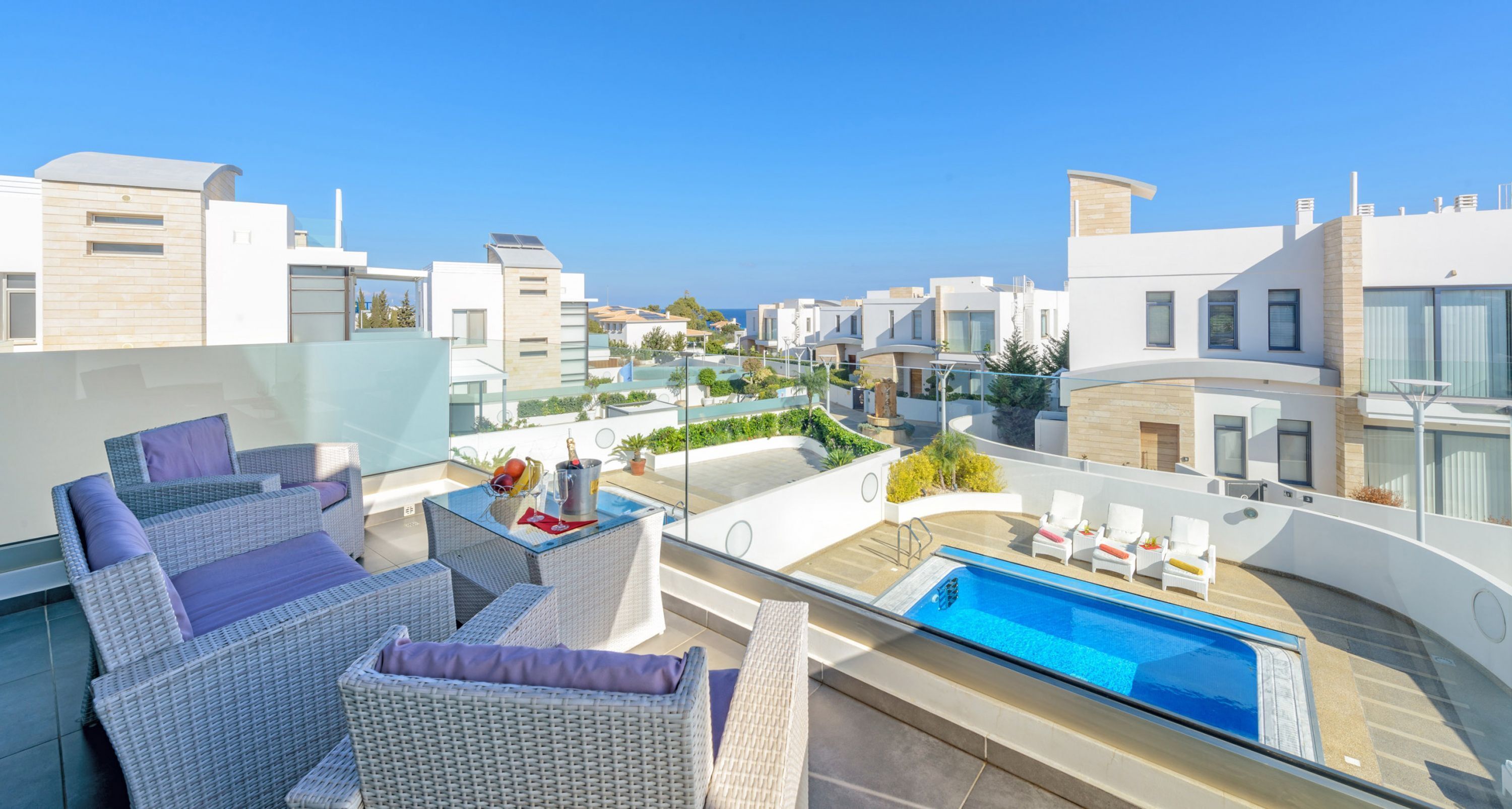 A rooftop terrace with a swimming pool, wicker furniture, and a view of the cityscape.