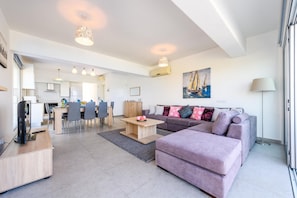 A modern living room with a sofa, a coffee table, and a dining area with chairs and a table.