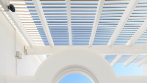 Un couloir intérieur mène à un patio extérieur d’où l’on a une vue dégagée sur le ciel.