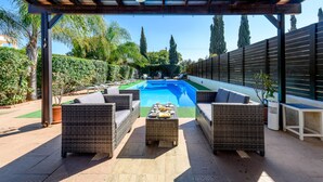 A covered outdoor area with a pool, wicker furniture, and a ceiling fan. - Villa Penelope in Protaras (Paralimni)