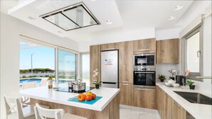 Cocina moderna con isla central, electrodomésticos integrados y vista a una piscina.