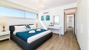 Habitación de hotel moderna con una cama grande, un escritorio y vistas al cielo a través de las ventanas.